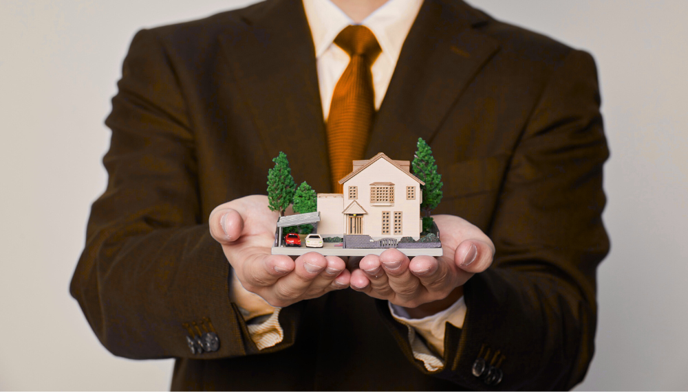 homme qui tient une maison miniature dans ses mains