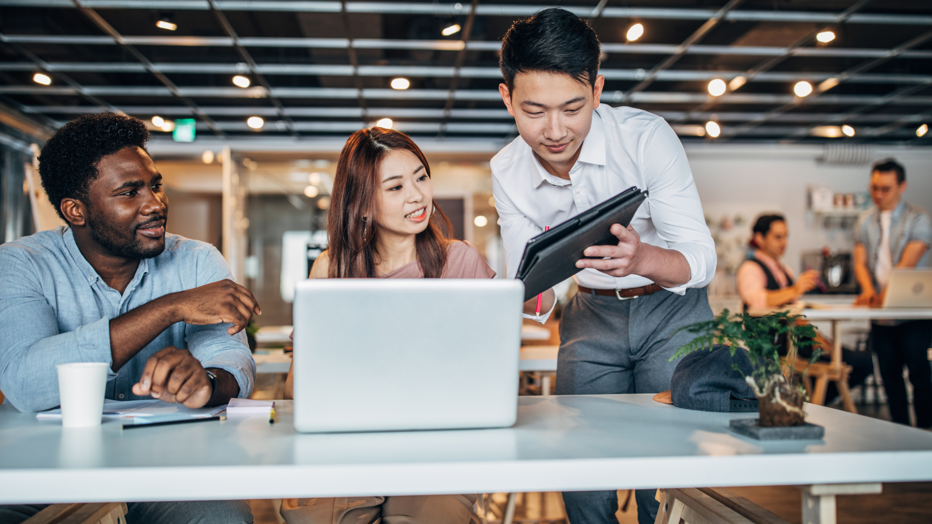 Des personnes travaillant autour d'un ordinateur dans un open space